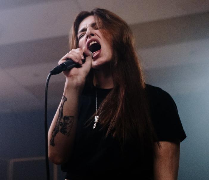 metal singer with long dark hair holding a microphone